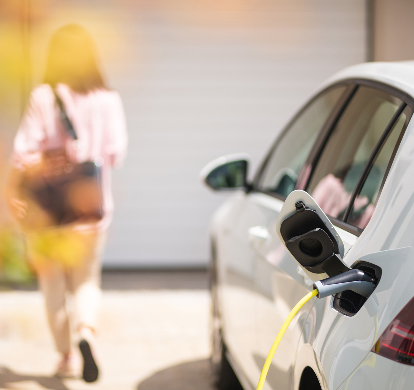 Eine Frau neben einem weißen Elektroauto