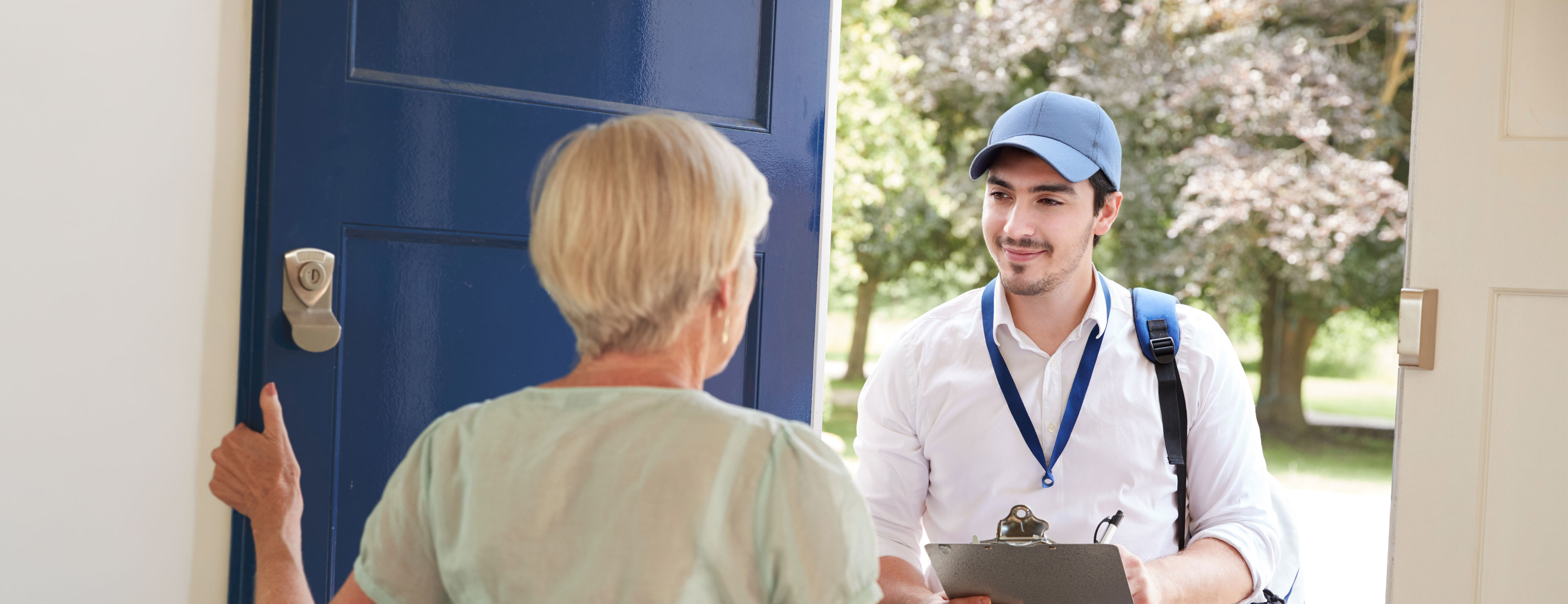 Eine ältere Dame öffnet einem jungen Mann die Tür