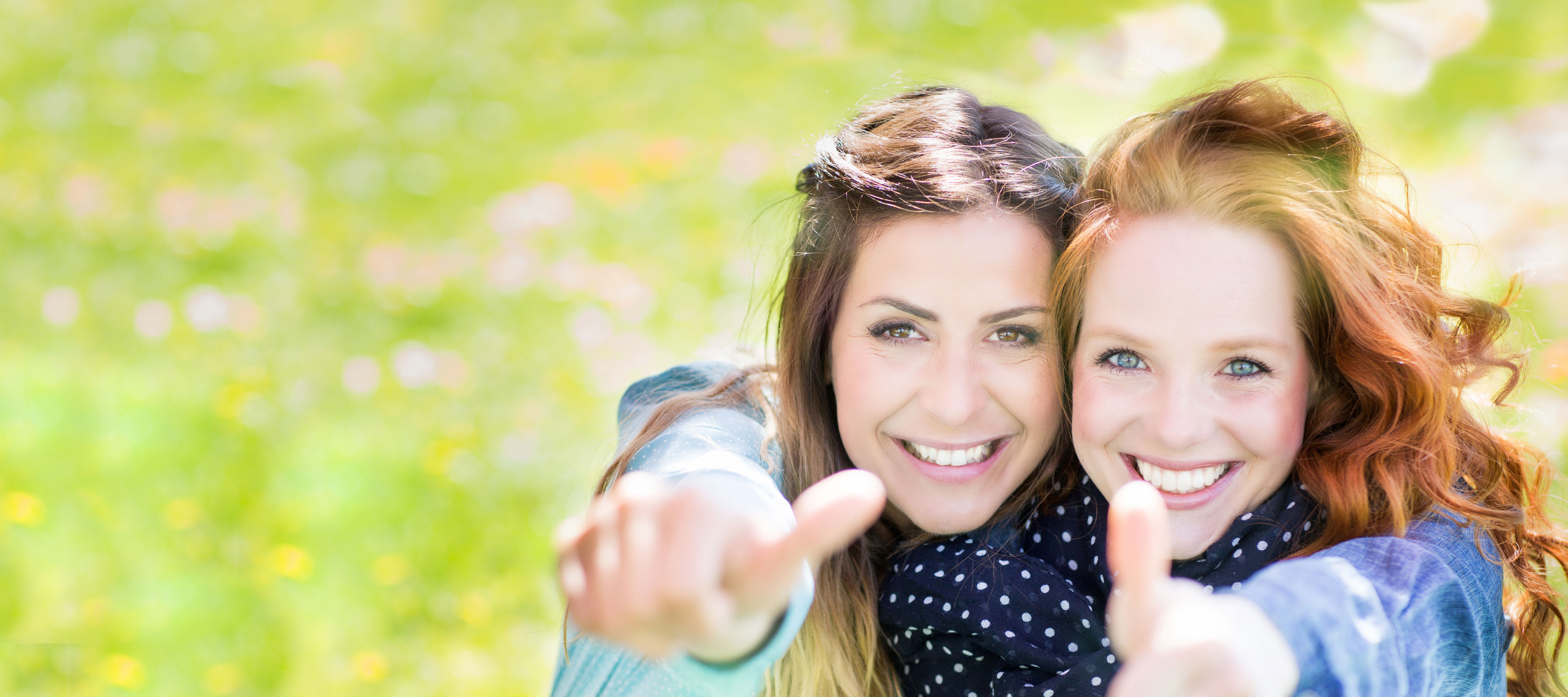 Zwei junge Frauen strecken den Daumen hoch.