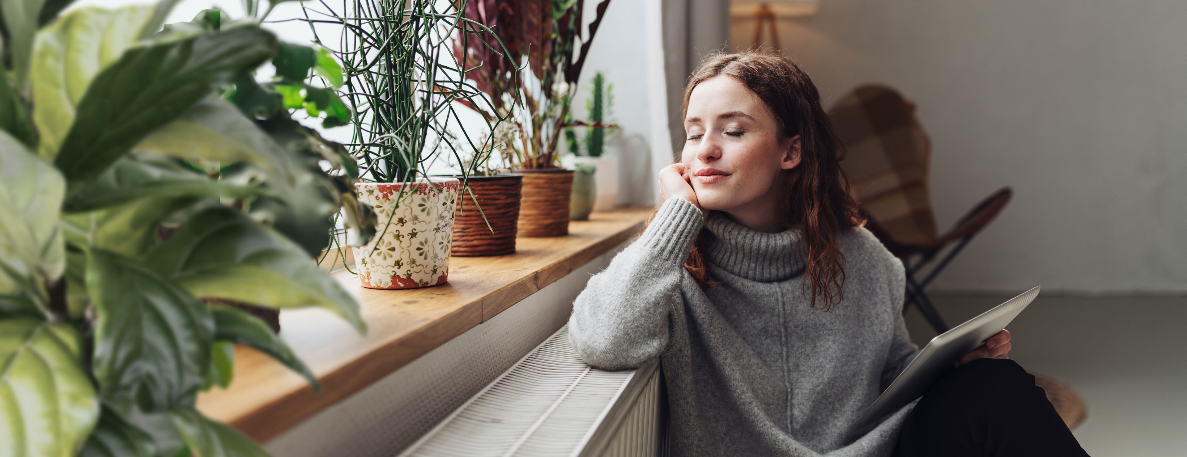 Junge Frau sitzt Entspannt vor ihrer Heizung mit ihrem neuen günstigen Gastarif.