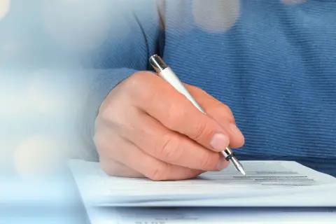 Eine Hand unterschreibt einen Vertrag.