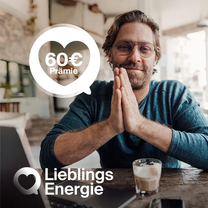 Mann mit Brille und Bart sitzt am Tisch und hält die Handflächen zusammen vor der Brust.