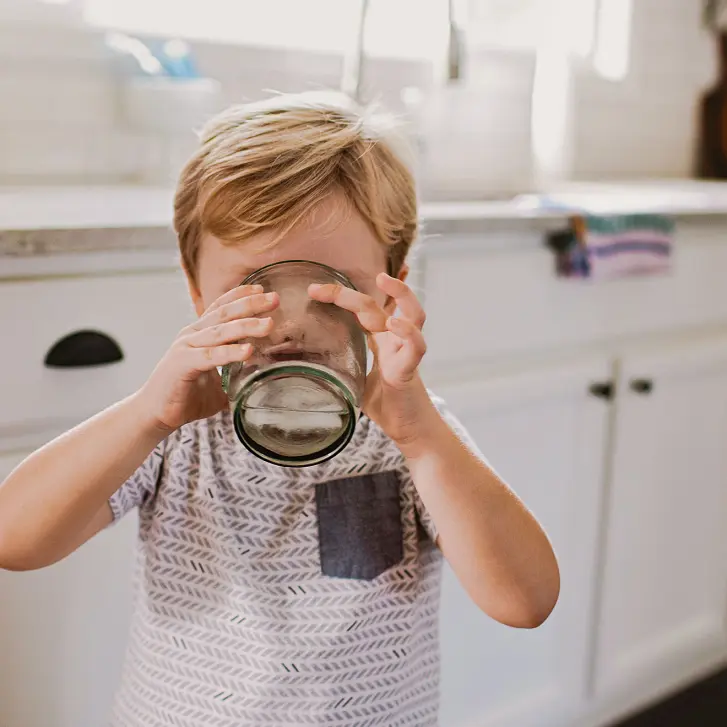 Kind trinkt Wasser aus dem Glas.