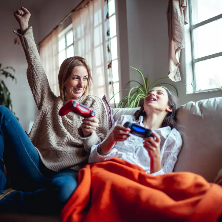 Mutter und Tochter spielen mit der Spielekonsole.