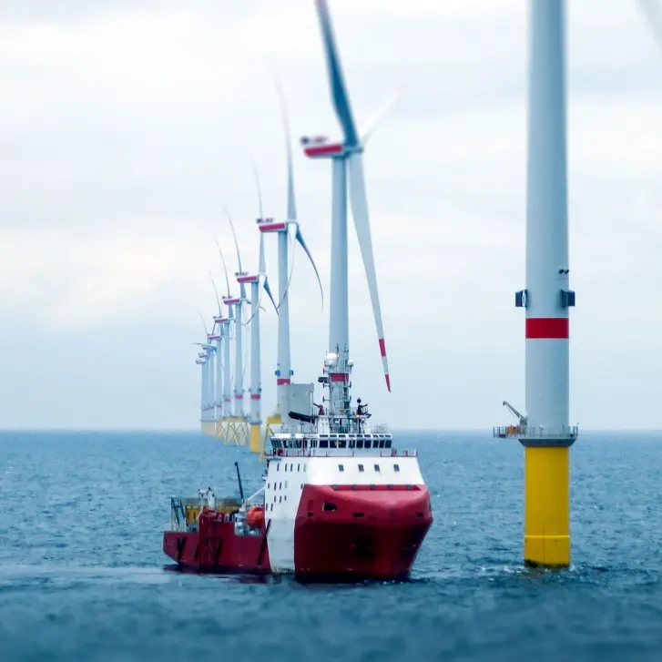 Ein Schiff vor mehreren Offshore-Windkraftanlagen auf dem Meer