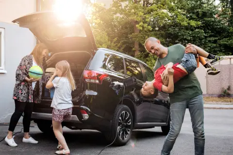 Eine Familie packt gemeinsam ihr E-Auto für den Urlaub.