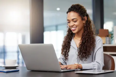 Junge Frau sitzt vor dem Laptop und lächelt