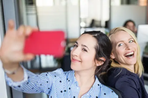 Die Frauen im Büro haben gute Laune und machen Selfies.