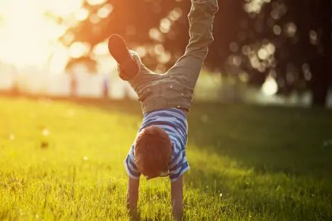 Junge macht einen Handstand auf der Wiese.
