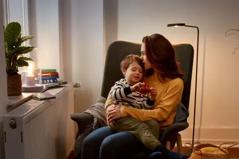 Mutter und Sohn sitzen im Sessel vor der Heizung.
