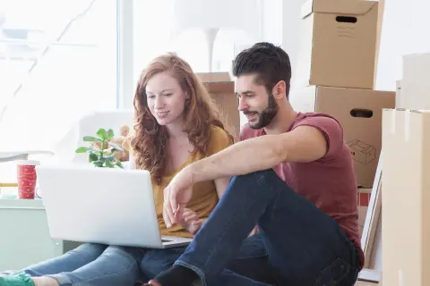 Junges Pärchen sitzt vor dem Laptop.