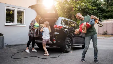 Eine Familie packt ihr Elektroauto, das an der Wallbox angeschlossen ist.