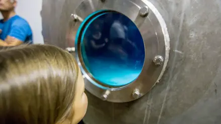 Mädchen schaut in einen Wasserfilter im Wasserwerk
