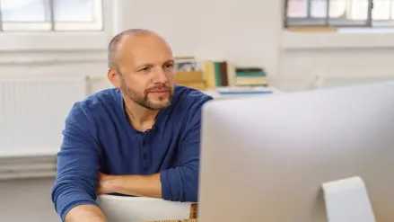 Mann sitzt vor Computer.