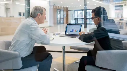 Zwei Menschen sitzen im Büro und schauen auf einen Laptop