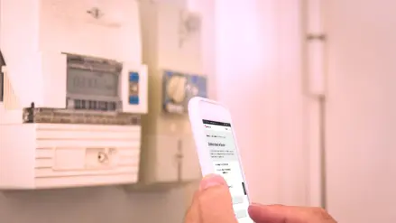Handy in der Hand vor dem Stromzähler