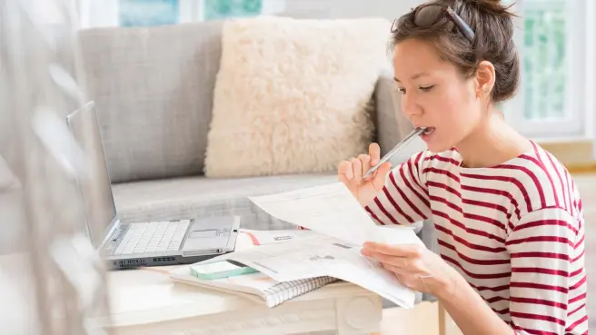 Eine Frau sitzt mit Rechnungen vor einem Laptop