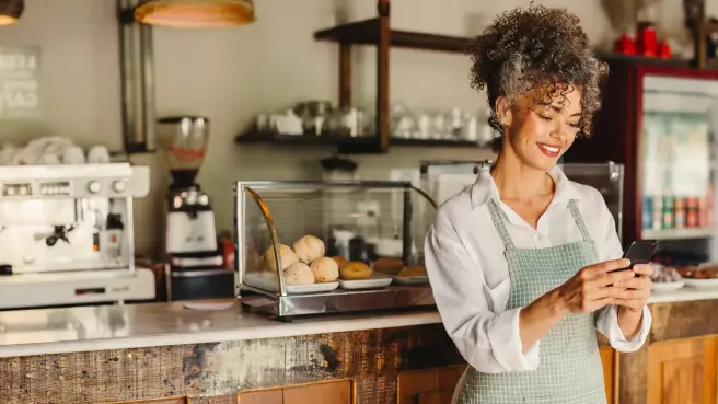 Ein Mann in Arbeitskleidung steht in einer Werkstatt und schaut auf einen Laptop