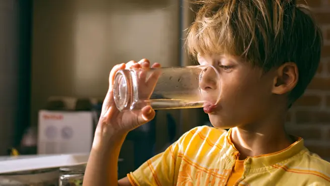 Junge trink Wasser aus einem Glas.