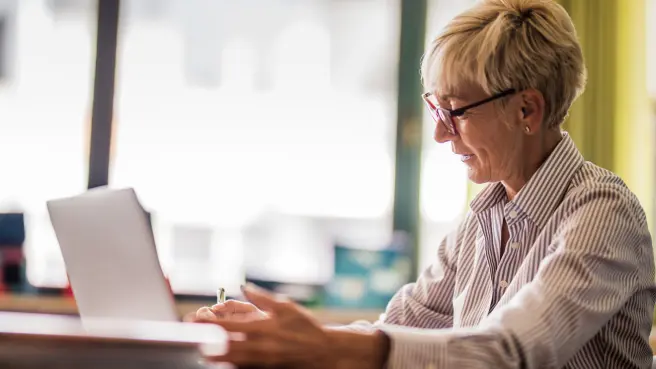Lehrerin schaut am Laptop nach Unterrichtsmaterial.
