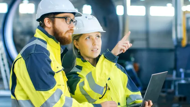 Zwei Menschen stehen mit Plan auf einer Baustelle