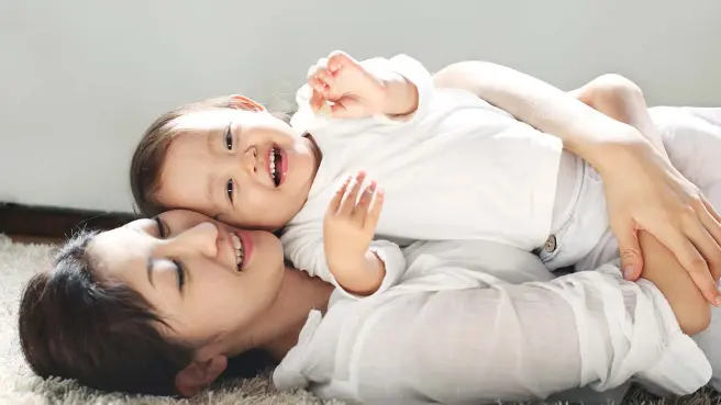 Mutter und Tochter liegen kuschelnd auf dem Fußboden.