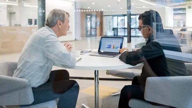 Zwei Menschen sitzen im Büro und schauen auf einen Laptop