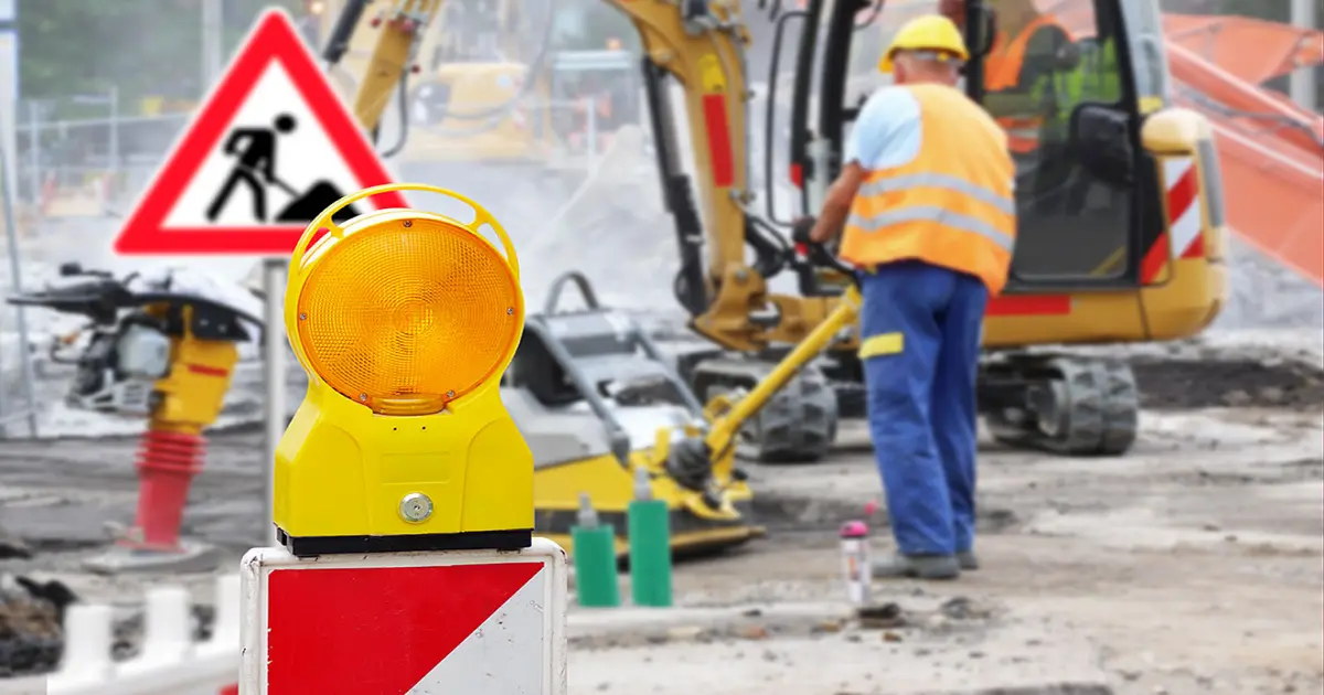 Ein Bauarbeiter und ein kleiner Bagger auf einer Baustelle