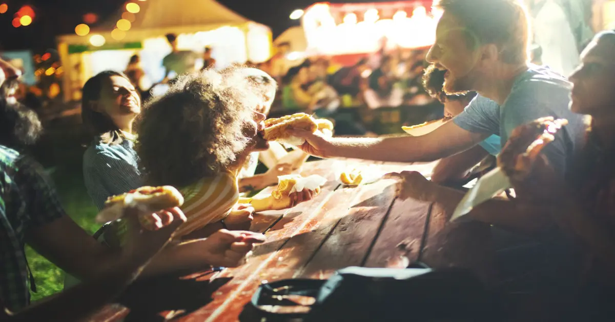 Familie isst auf einem Straßenfest Pizza.