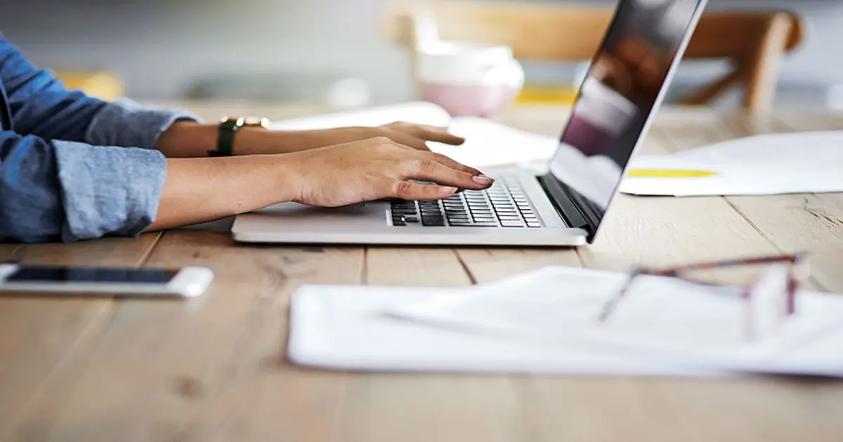 Person schreibt auf dem Laptop.