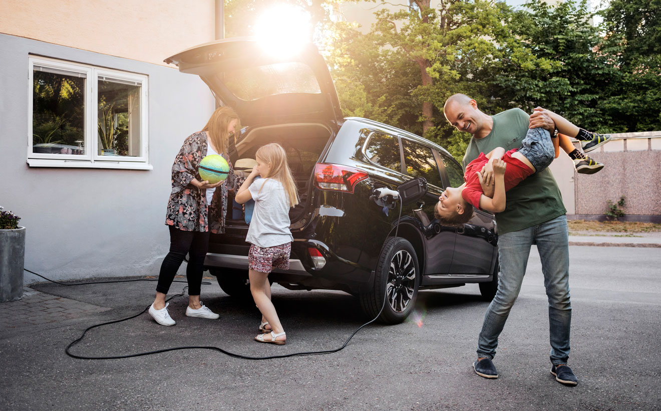 Eine Familie packt ihr Elektroauto, das an der Wallbox angeschlossen ist.