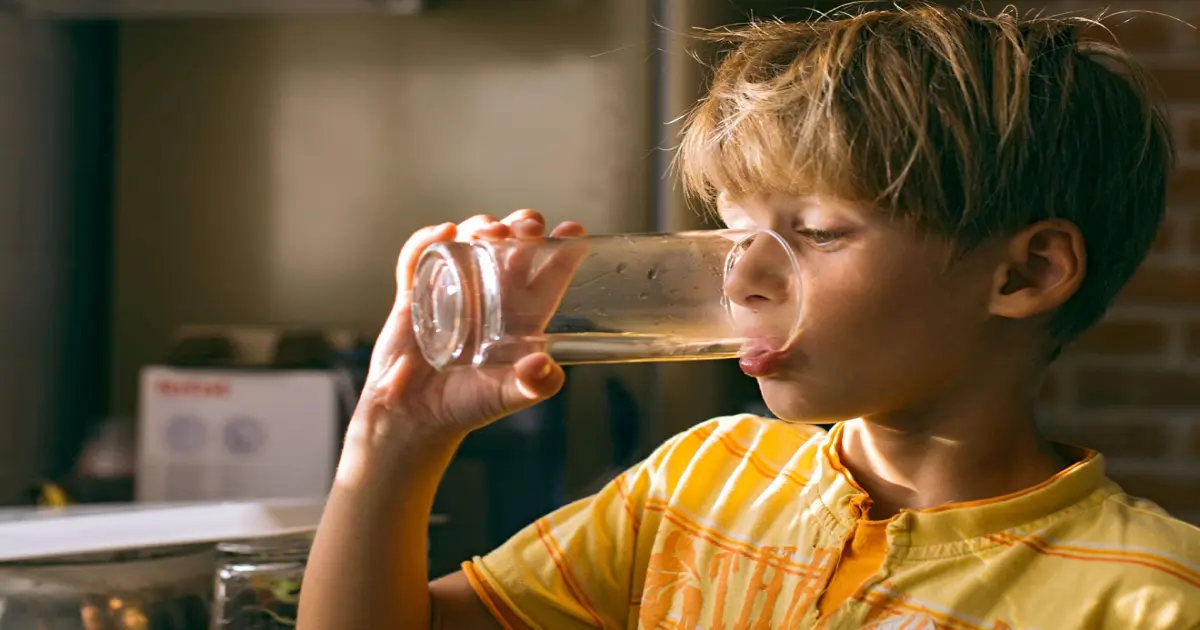 Junge trink Wasser aus einem Glas.