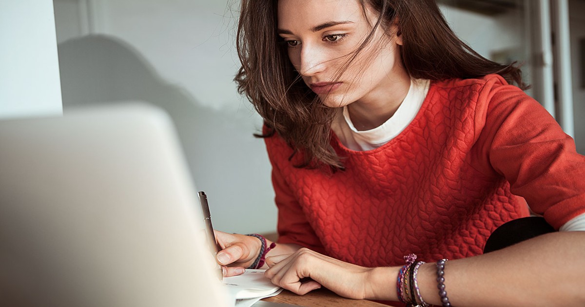 Junge Frau schreibt am Laptop.