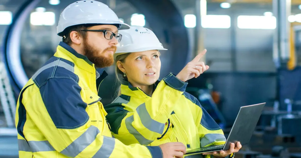 Zwei Menschen stehen mit Plan auf einer Baustelle