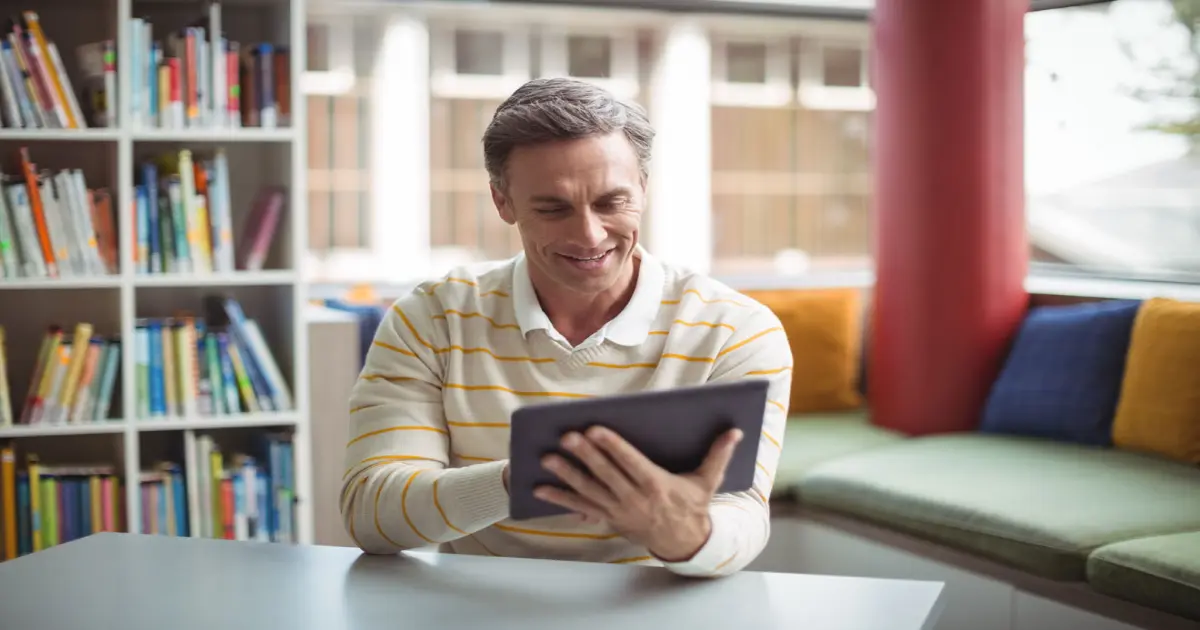 Mann mit Tablet in der Bücherei.