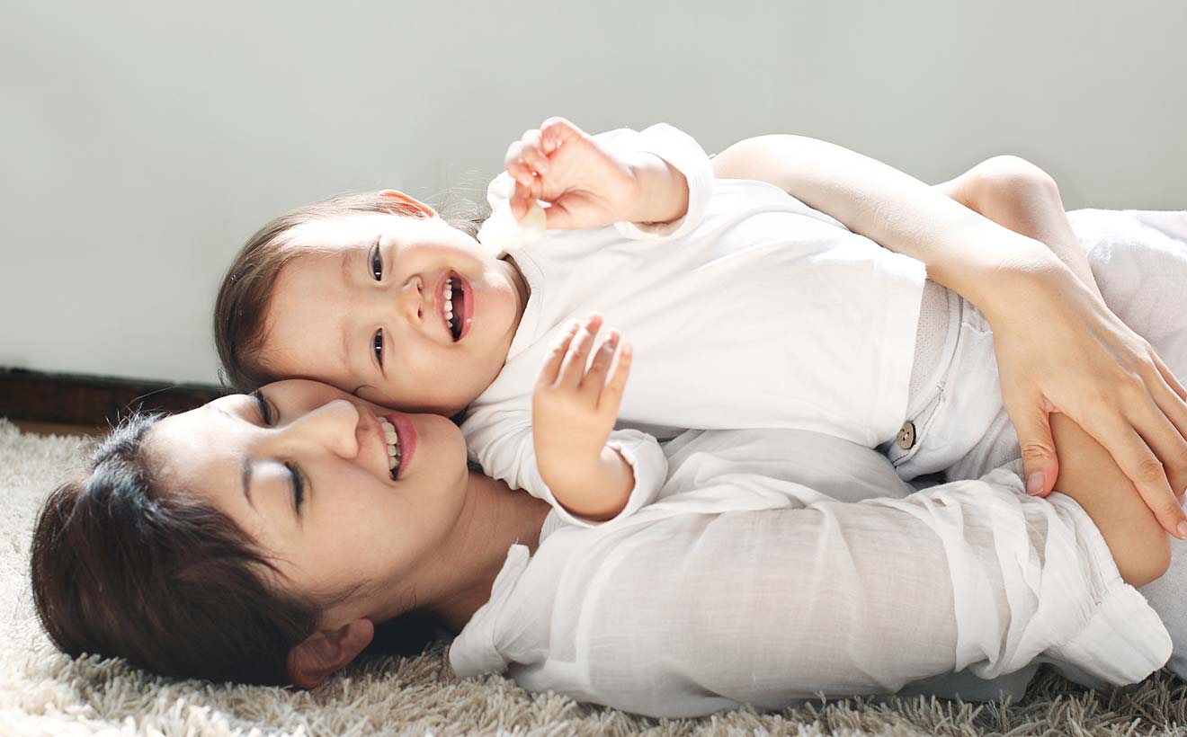 Mutter und Tochter liegen kuschelnd auf dem Fußboden.