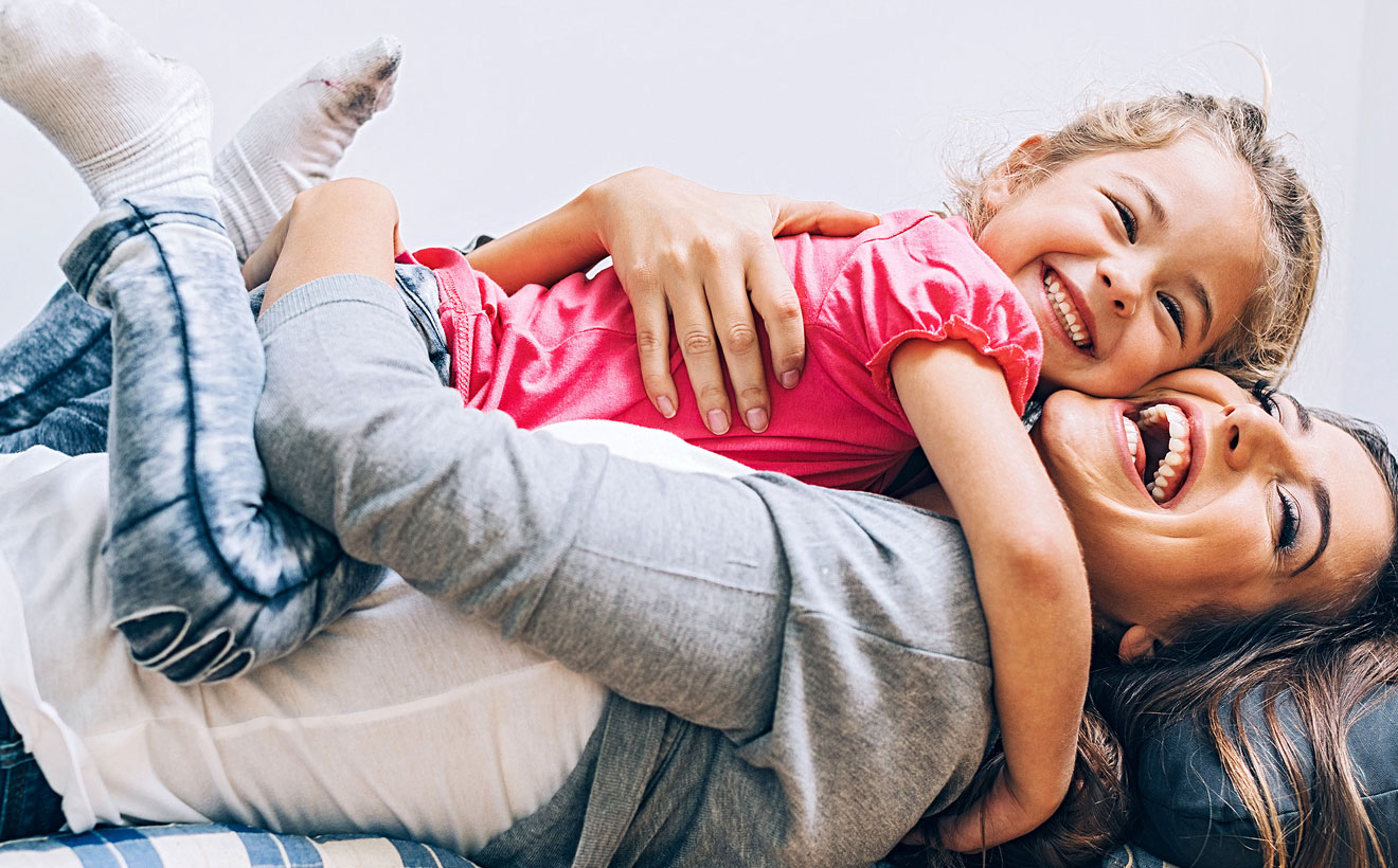 Mutter und Tochter kuscheln auf dem Sofa.