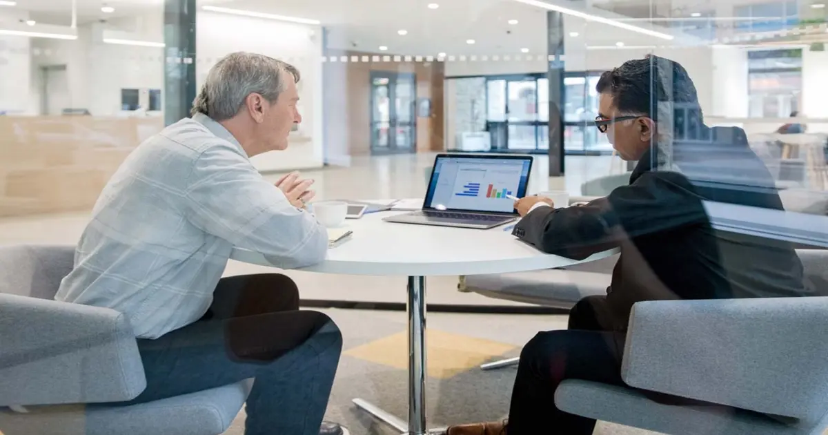 Zwei Menschen sitzen im Büro und schauen auf einen Laptop