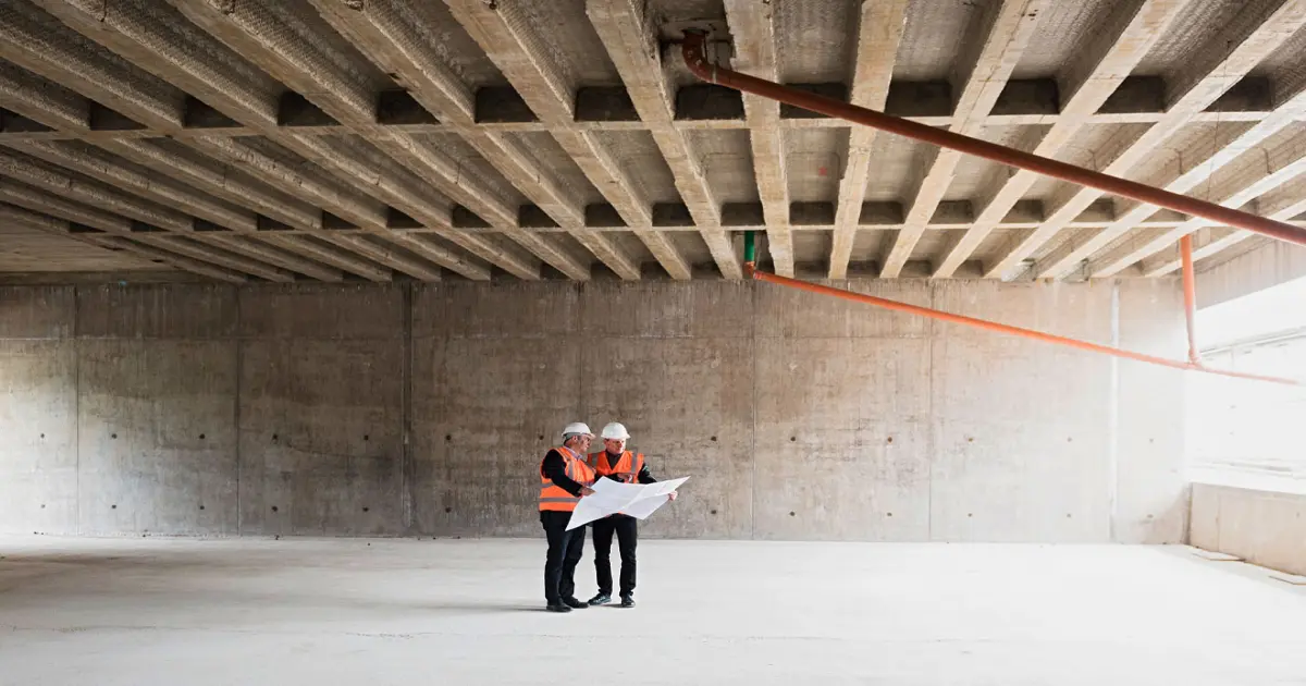 Bauleiter mit Plan im Rohbau.