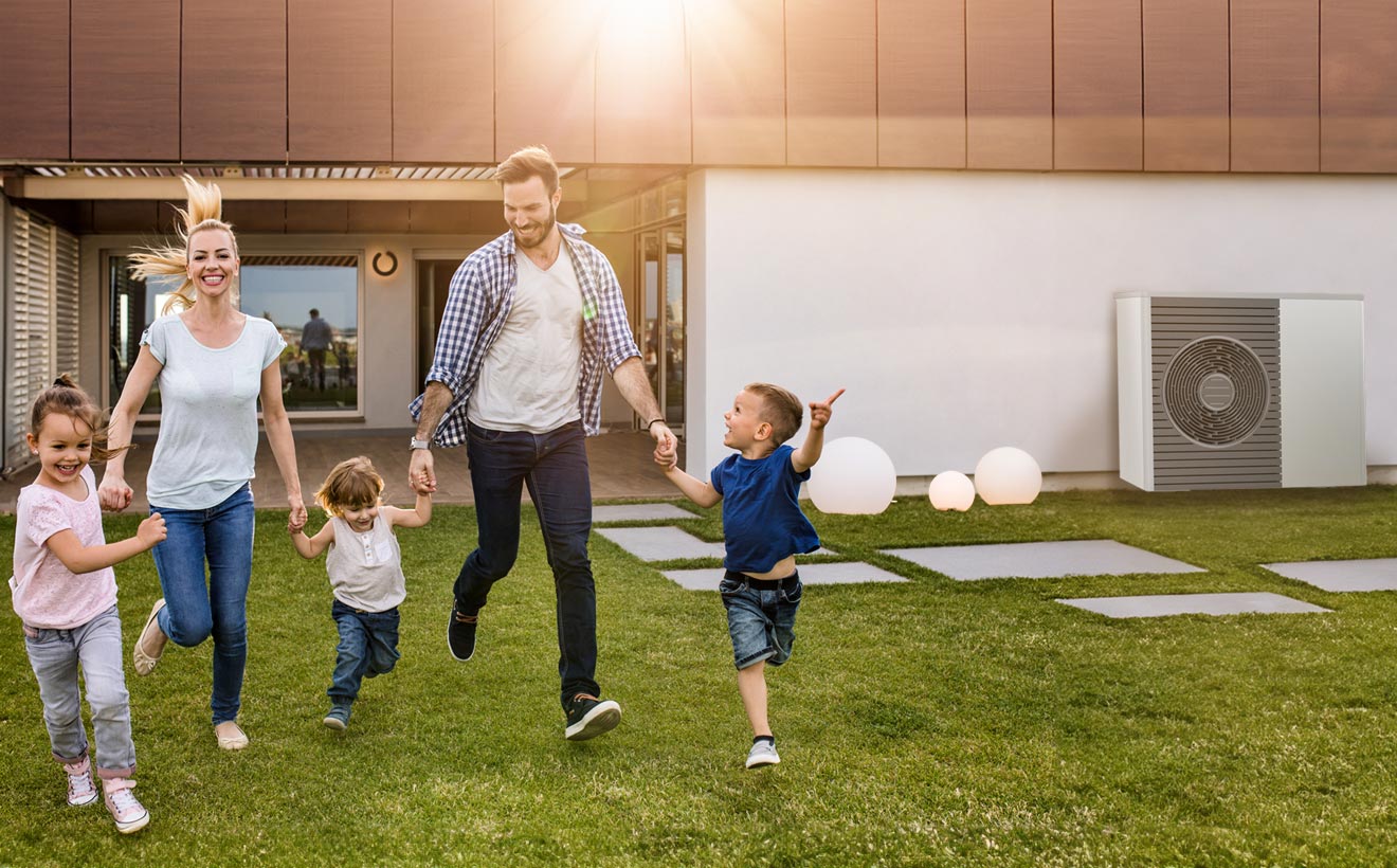 Familie im Garten vor einem Haus mit Wärmepumpe 