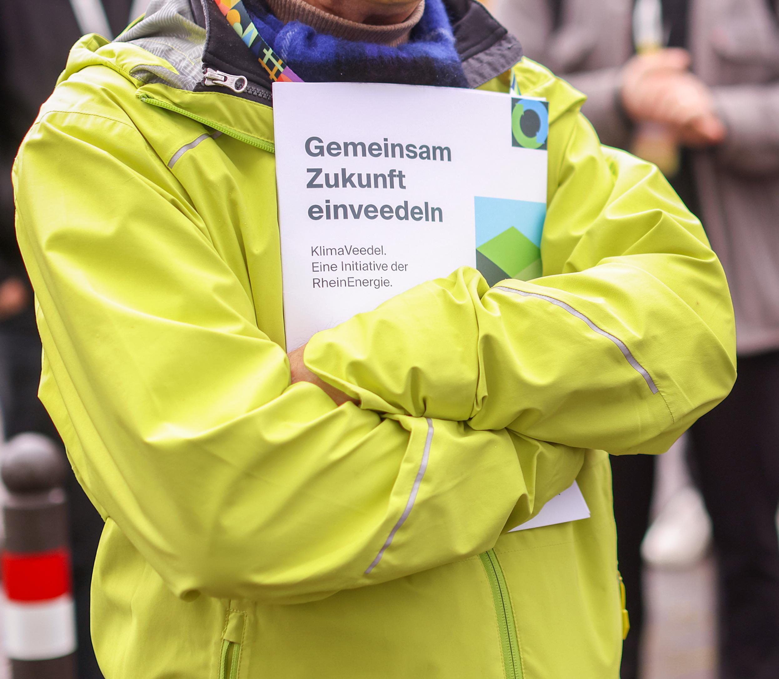 Mann in gelber Jacke mit KlimaVeedel-Prospekt