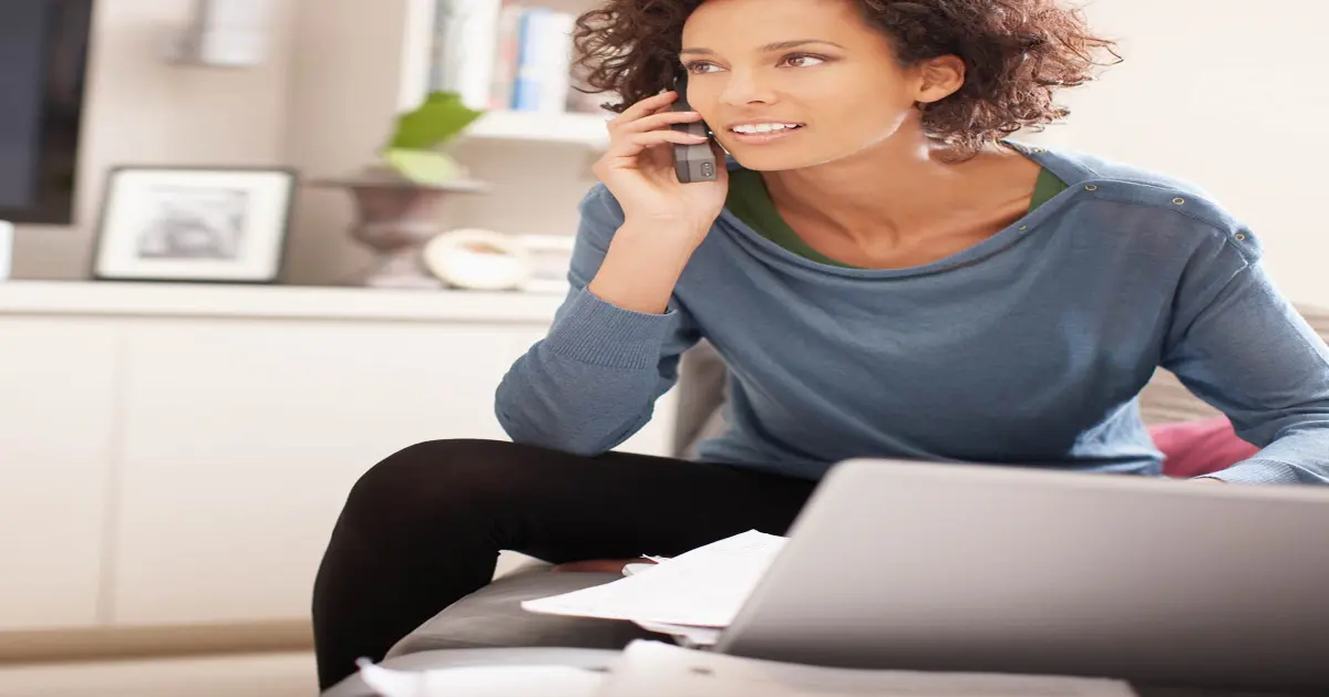 Eine Frau sitzt vor dem Laptop und telefoniert