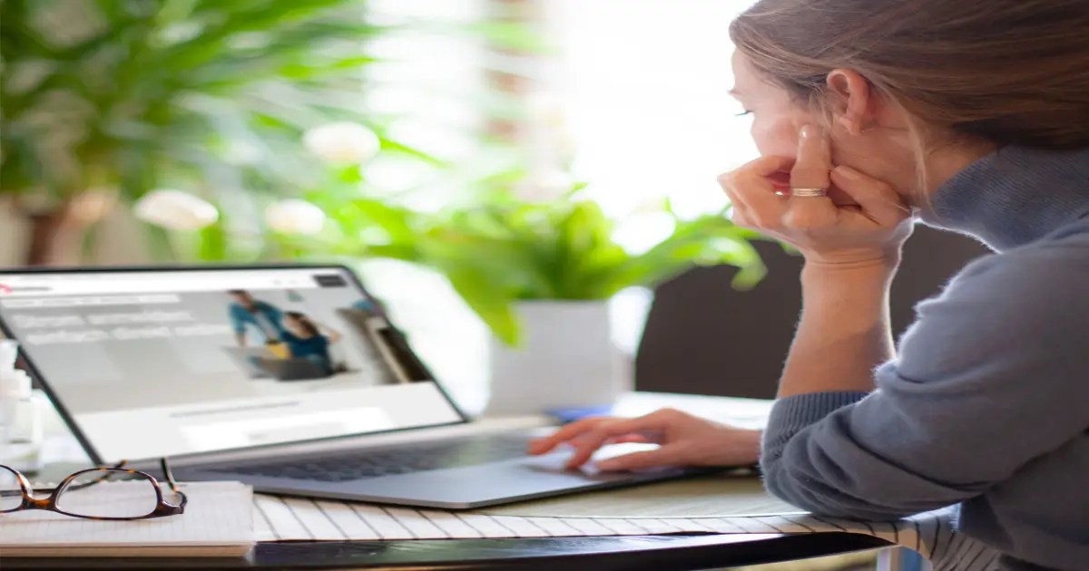 Eine Frau sitzt vor ihrem Laptop und surft auf RheinEnergie.com