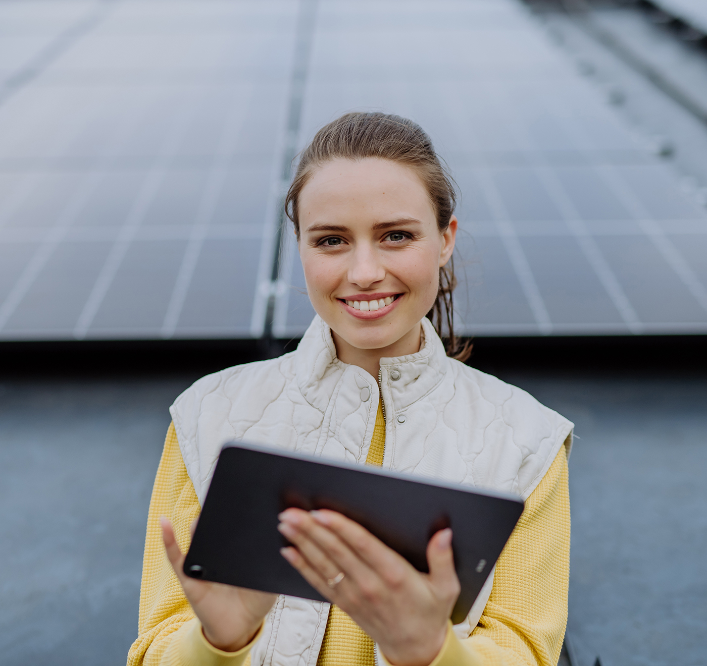Junge Frau mit Tablet vor Photovoltaikanlage
