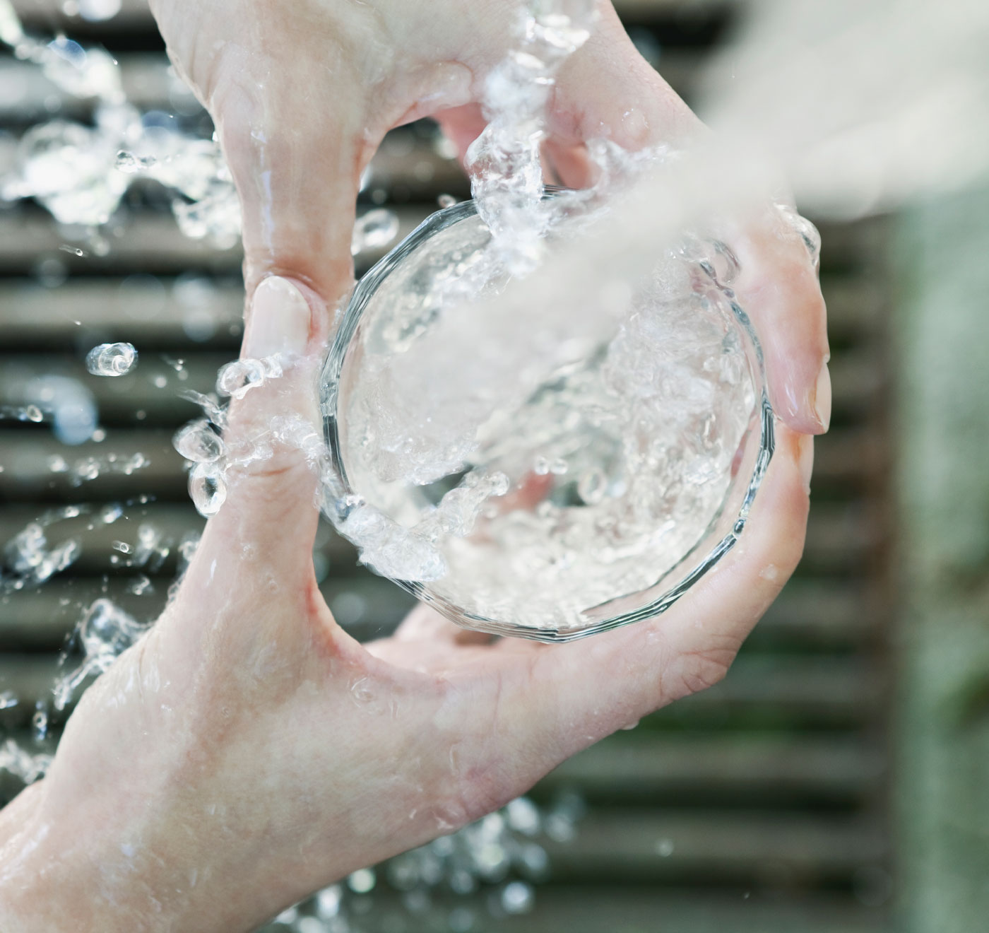 Wasserglas unter einem Trinkbrunnen.