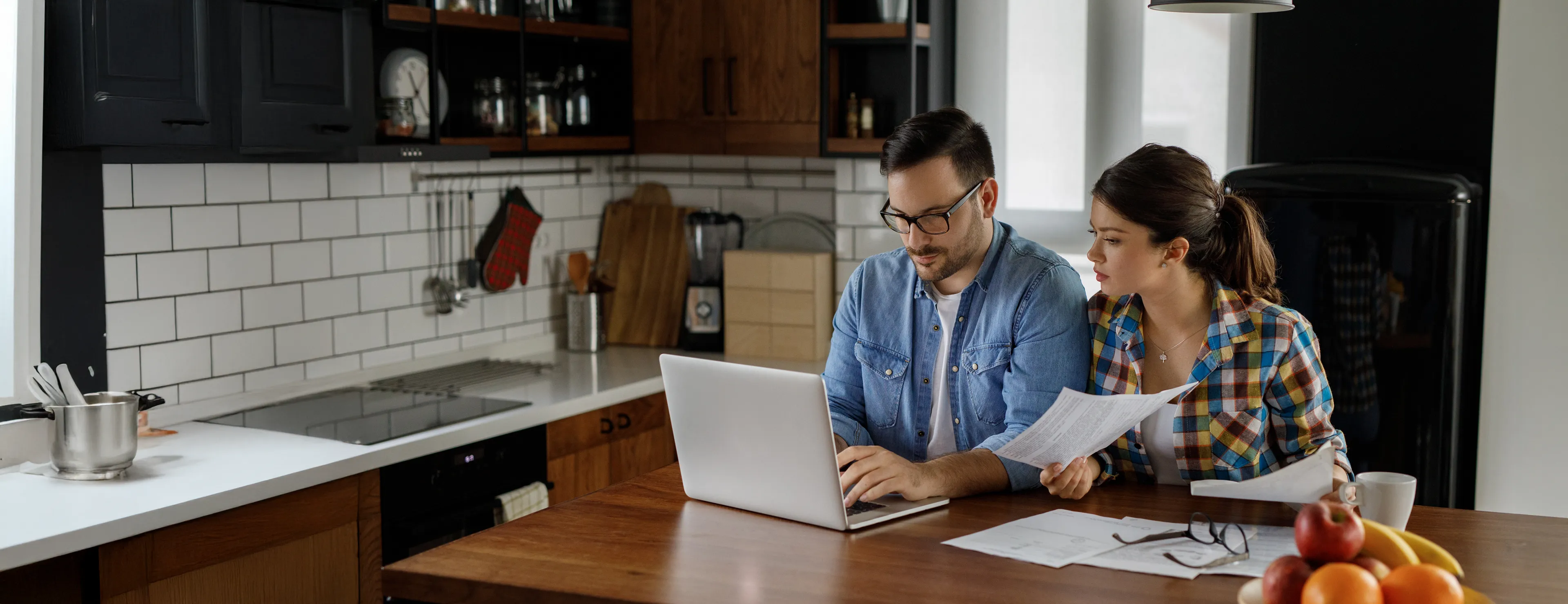 Ehepaar sitz in Küche vor Laptop
