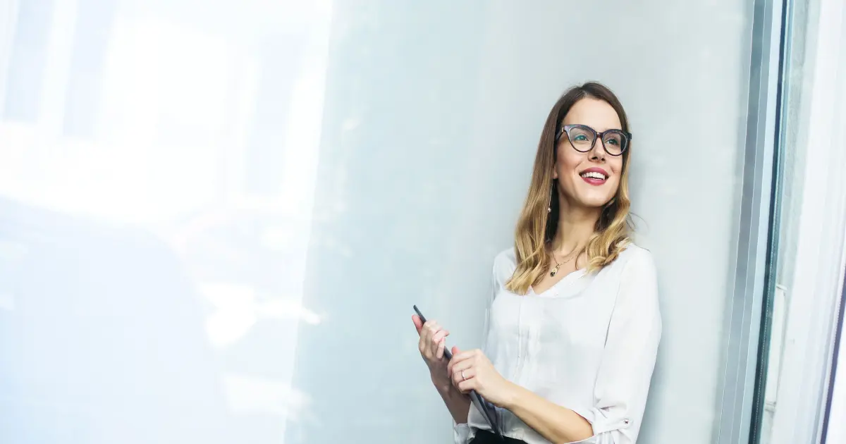 Junge Frau mit Tablet an eine Glasscheibe angelehnt.