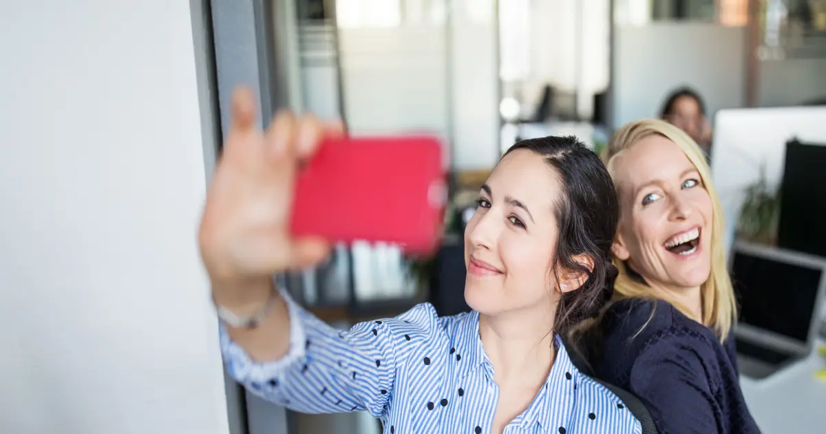 Die Frauen im Büro haben gute Laune und machen Selfies.