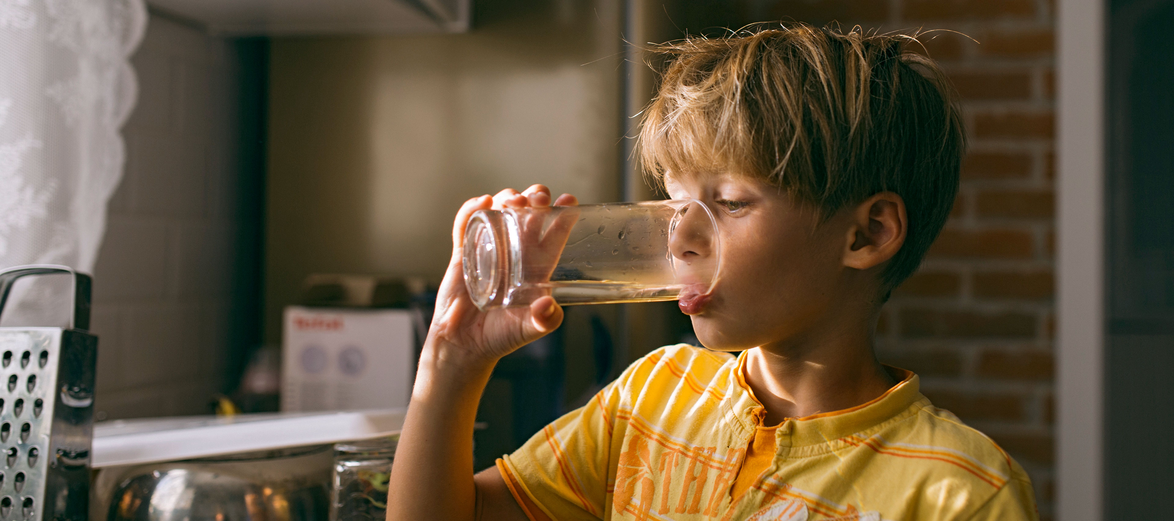 Ein Junge trinkt Wasser aus einem Glas.