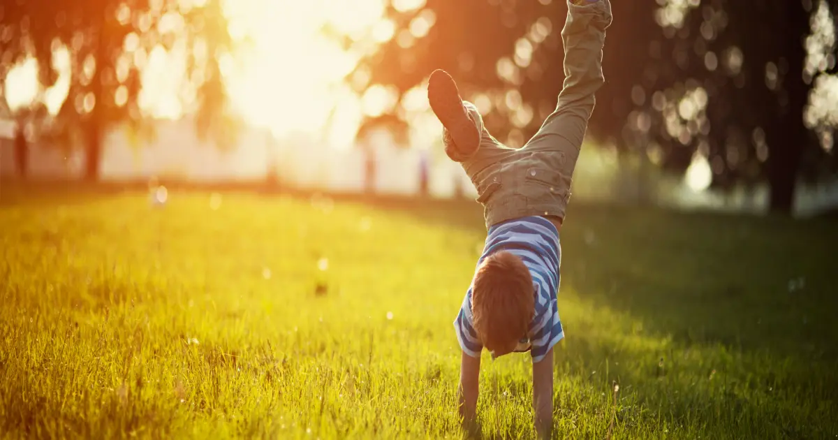 Junge macht einen Handstand auf der Wiese.